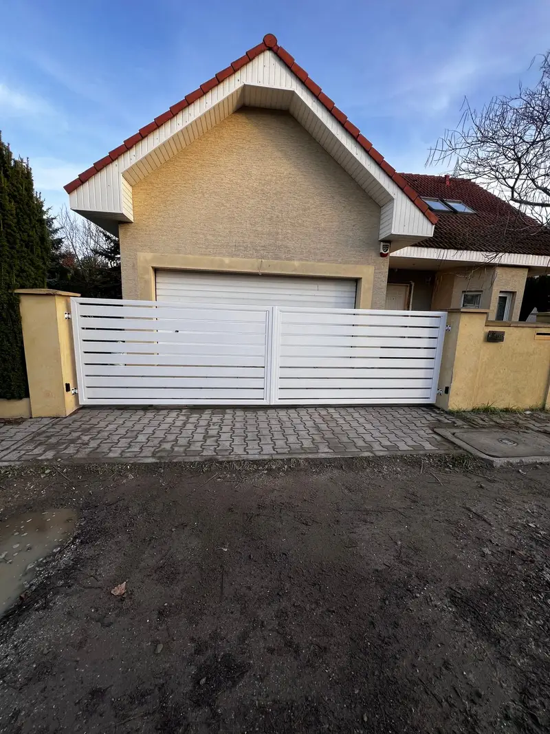 Biała brama z poziomych profili przed garażem domu z czerwonym dachem