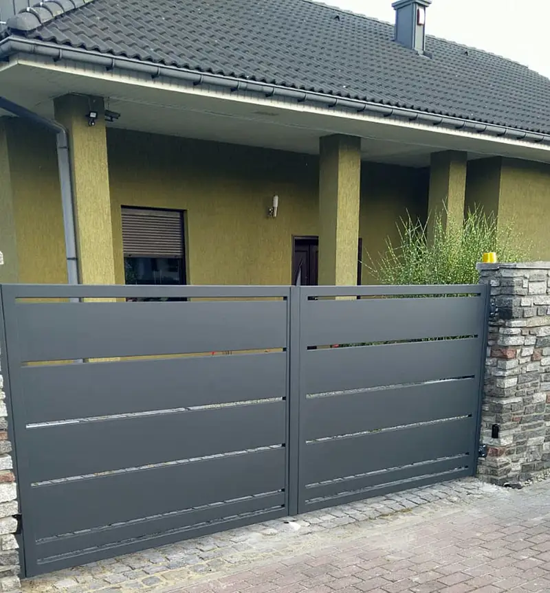 Grafitowa brama dwuskrzydłowa z wąskimi szczelinami przed domem