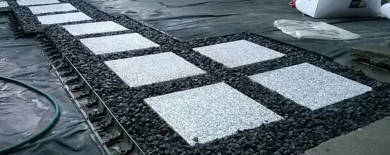 Układanie jasnych płyt na czarnym grysie i agrowłókninie